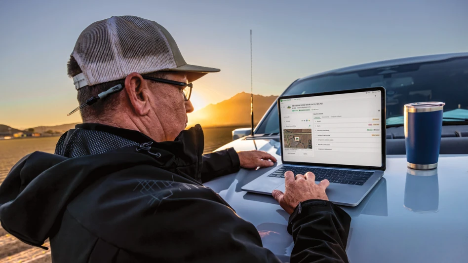 A man works at a laptop on the side of his truck