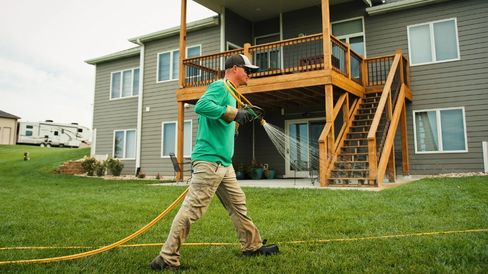 Summit Lawns employee sprays a backyard